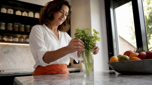 Een vrouw zet een bosje verse koriander in een glas water om het langer vers te houden.