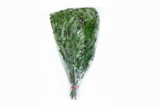 Bunch of green leaves in clear plastic wrap on a wooden surface